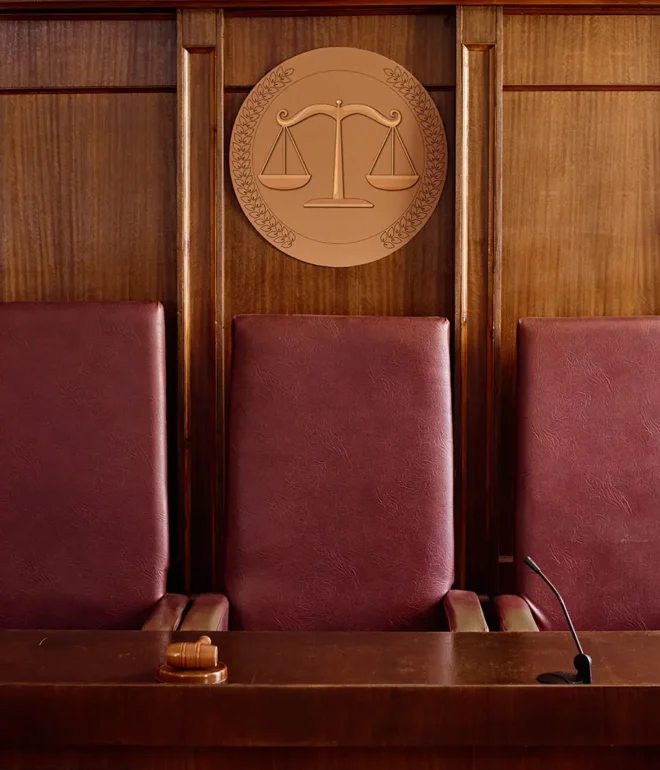 Three empty chairs in a jury box, located within a court room.