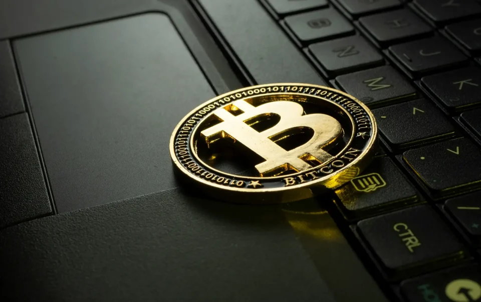 A representation of a golden bitcoin sitting on top of a laptop keyboard
