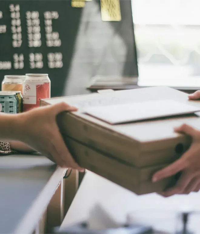 A close-up of a package being handed off to a waiting business owner