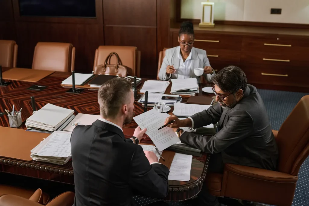 Two attorneys and a client in a boardroom. One points at a specific line on a legal document to a client.