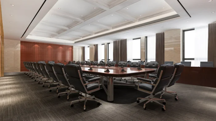 An empty board room filled with chairs arranged around a central table.