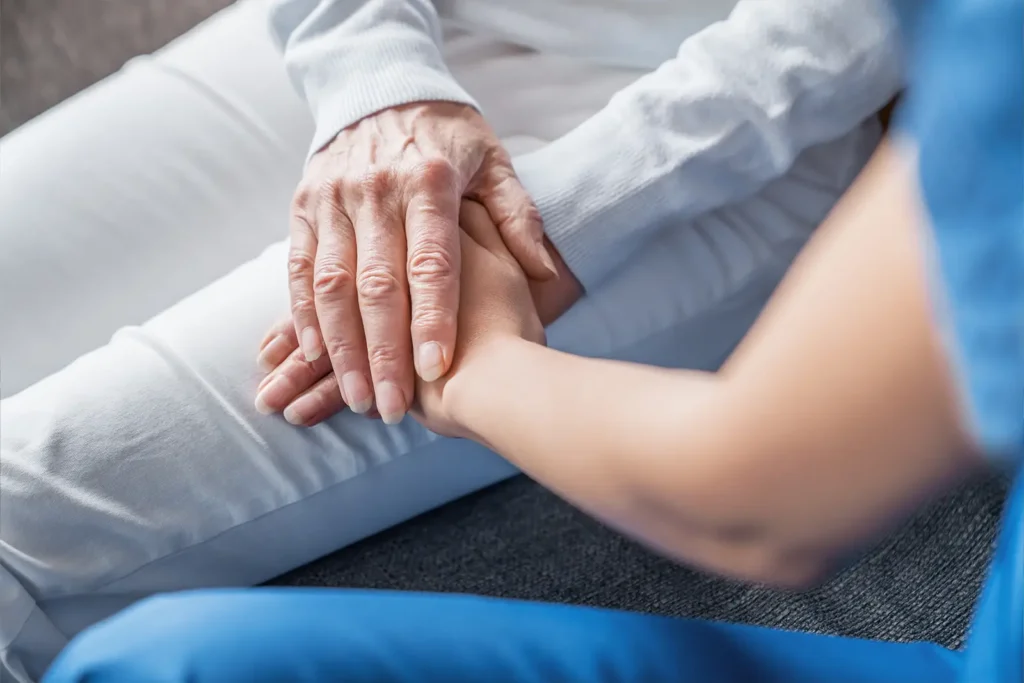 A close-up of an older woman's hands resting overtop of a family member's hands