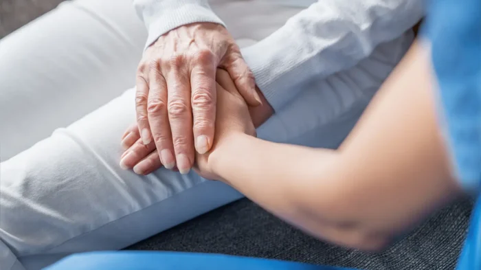 A close-up of an older woman's hands resting overtop of a family member's hands