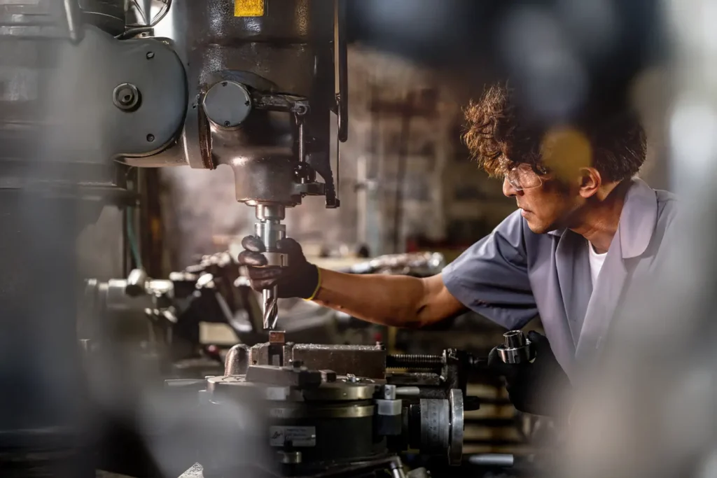 An assembly line worker adjusts a drill bit on an industrial machine