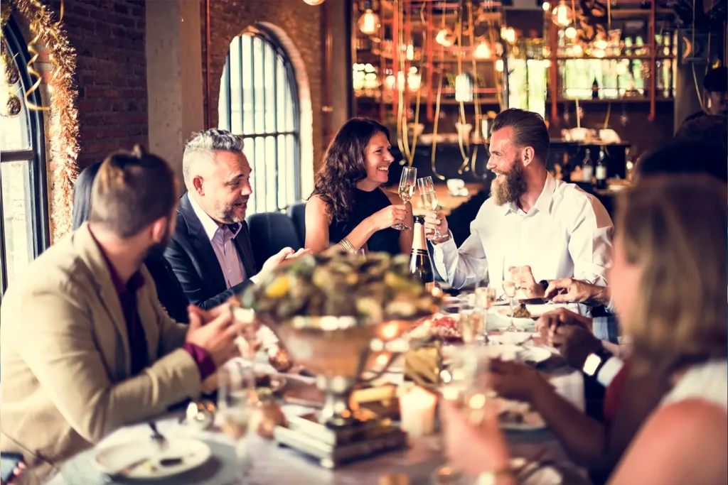 A group of diners laughing around a table at a fine dining restaurant