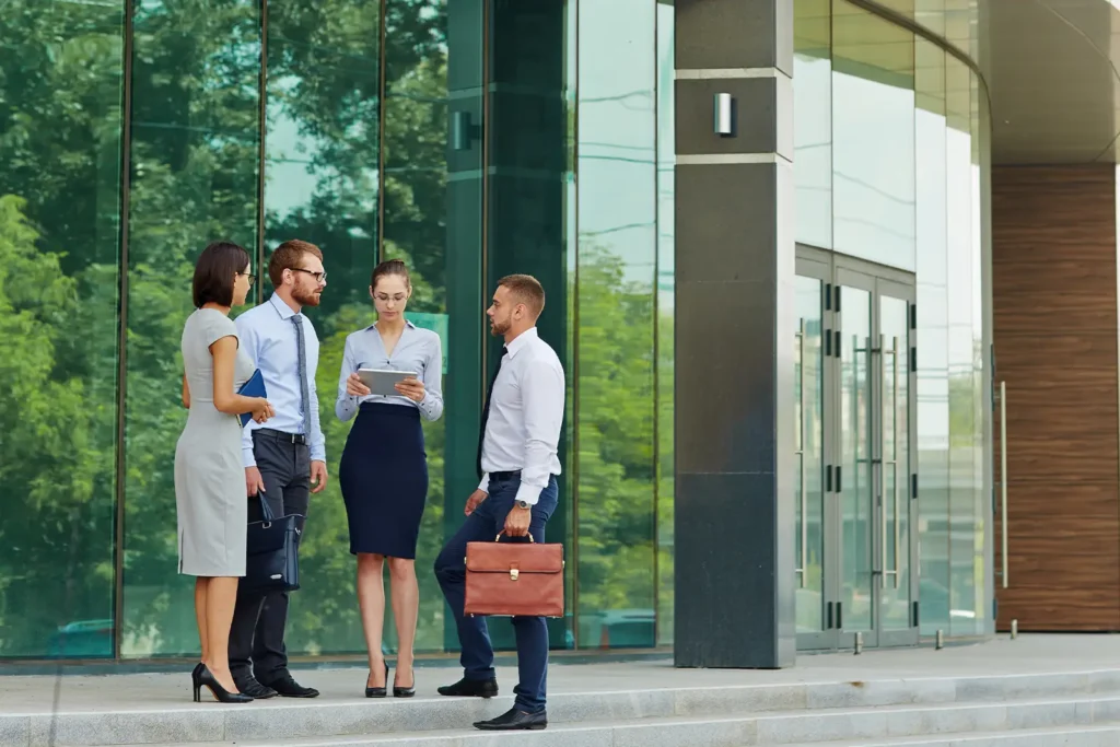 A group of four banking professionals outside of a large, modern office building