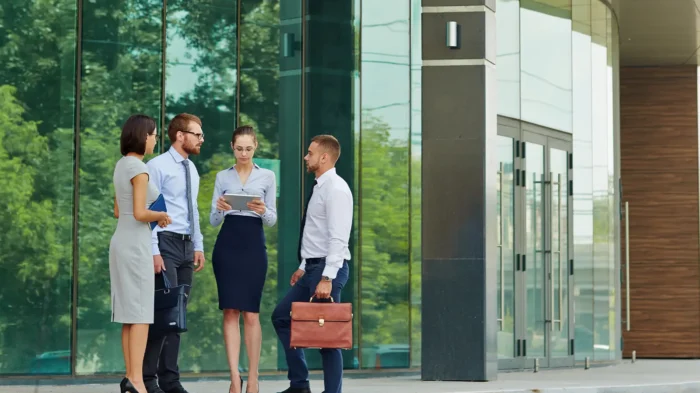 A group of four banking professionals outside of a large, modern office building