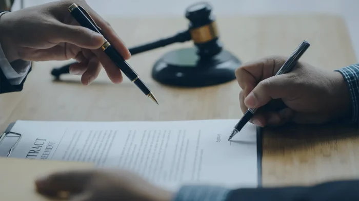 A close-up of a man's hand, signing a legal document