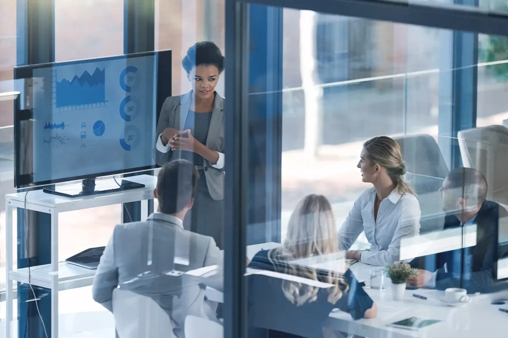 A group of business people in an office, watching a presentation