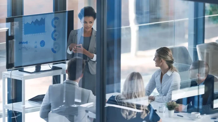 A group of business people in an office, watching a presentation