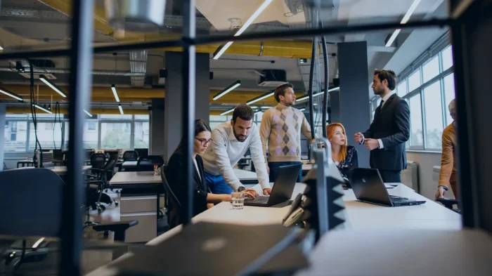 A group of professionals huddle around a computer, discussing their work