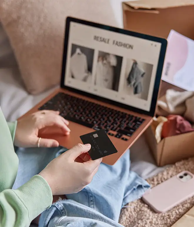 A woman holding a credit card enters her information while online shopping