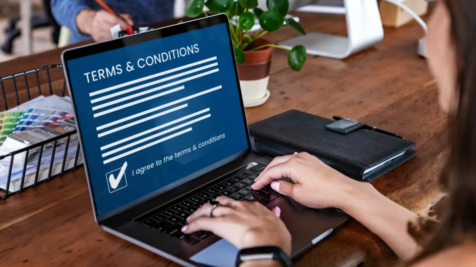 Closeup photo of a woman on a laptop, agreeing to terms and conditions on her screen