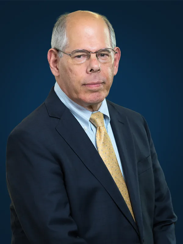 Attorney Tom DeWoskin poses for a portrait in front of a blue background